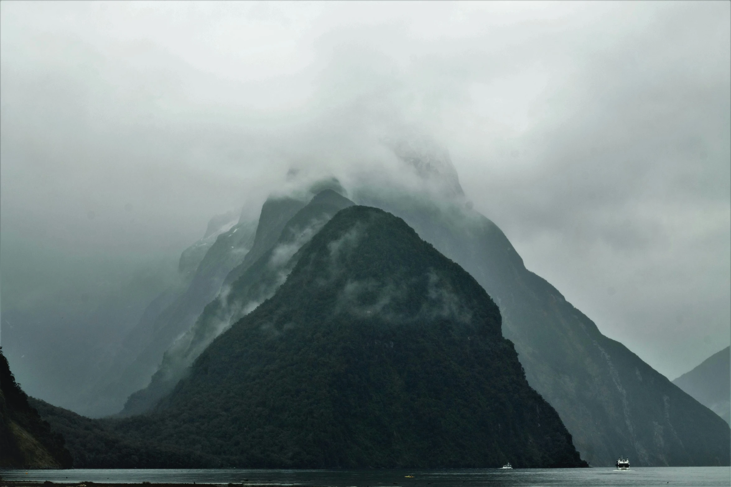 a boat traveling on the water in front of mountains