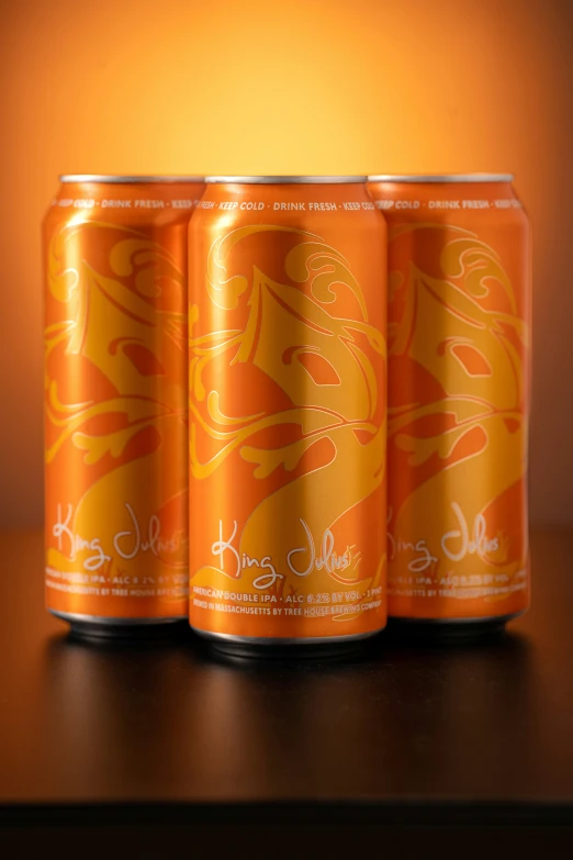 three orange soda cans with yellow liquid