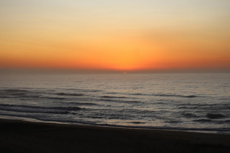 the sun is setting over the ocean and beach