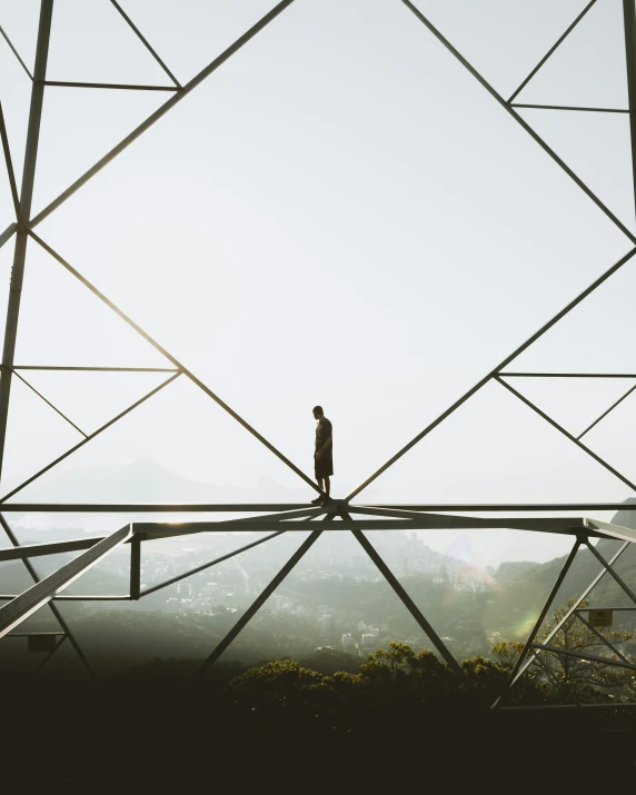 man standing on a suspension bridge over a forest