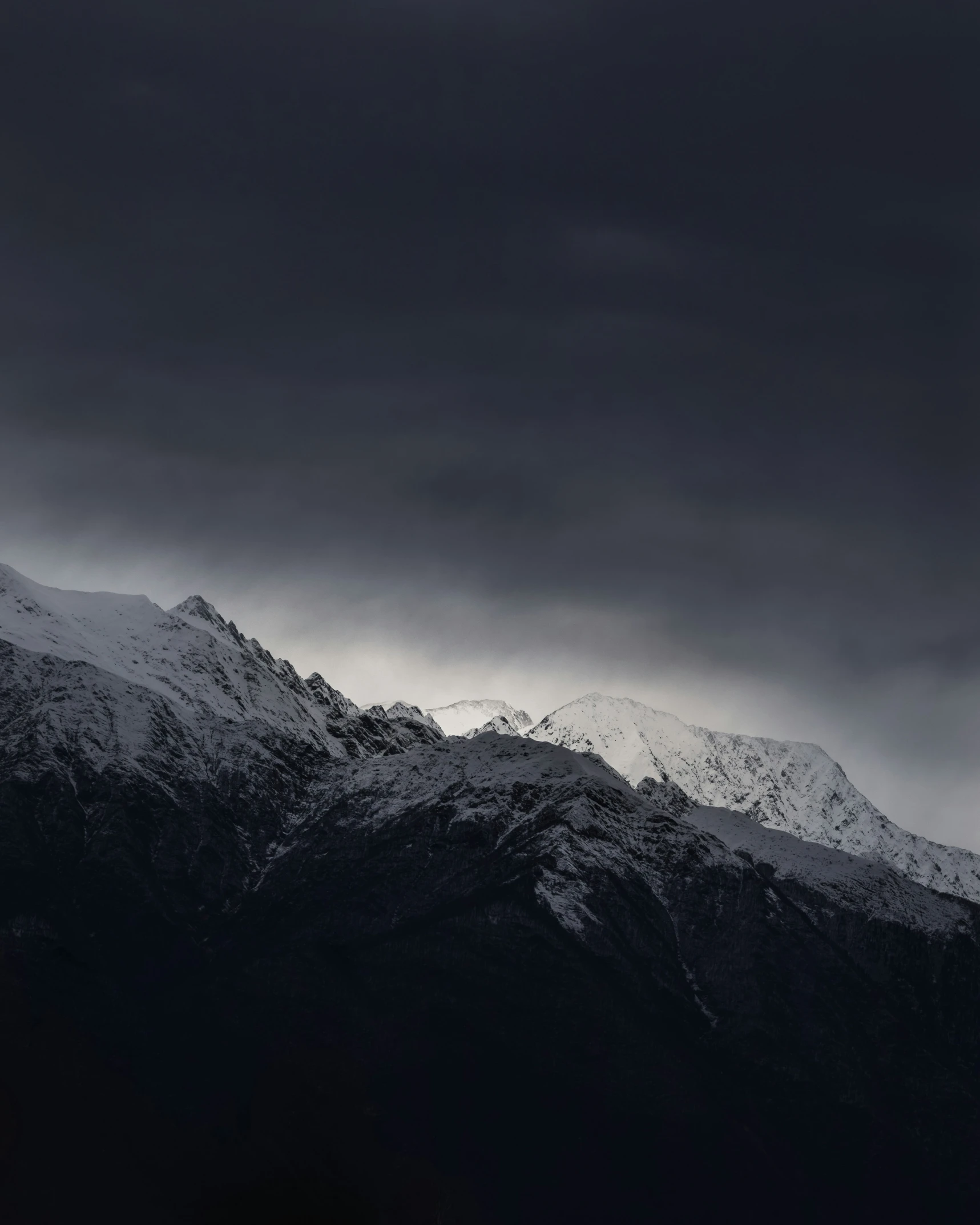 some snow mountains under a black cloudy sky