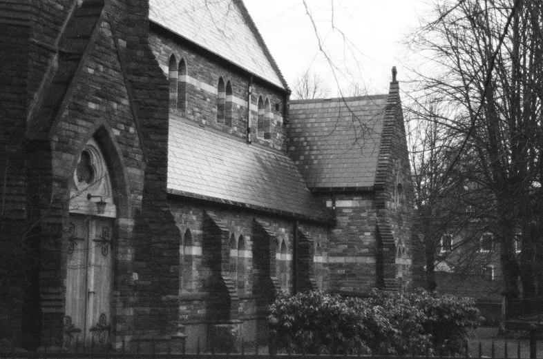 an old church with some tall windows near a large tree