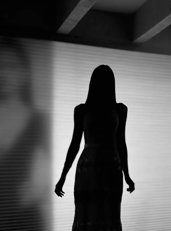 a silhouette of a woman standing in front of a curtain