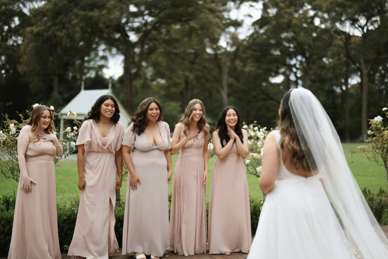 a bride and her bridal party stand at the beginning of a ceremony