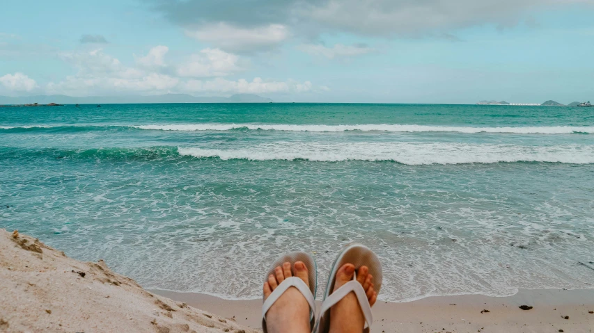 a person standing on a beach facing the ocean