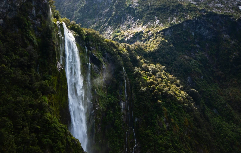 waterfall in between mountains with green vegetation on both sides