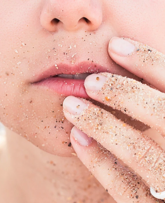 a woman eating a sand covered finger near her mouth