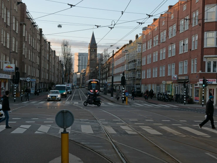 people walking on the sidewalk and passing vehicles down the street