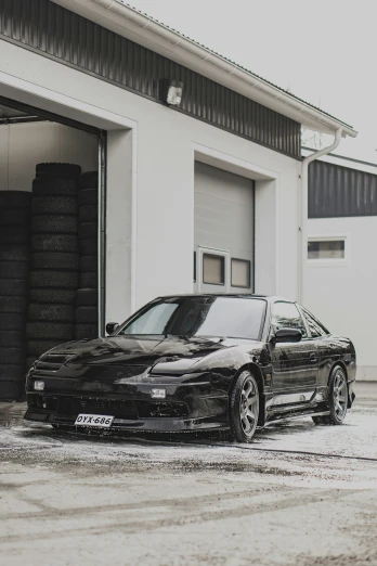 an elegant black sports car in front of a white garage
