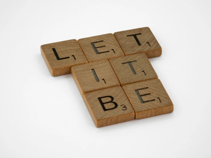 scrabble tiles in the shape of the letter t, that are made of letters spelling the word,'let's sit at b'e '