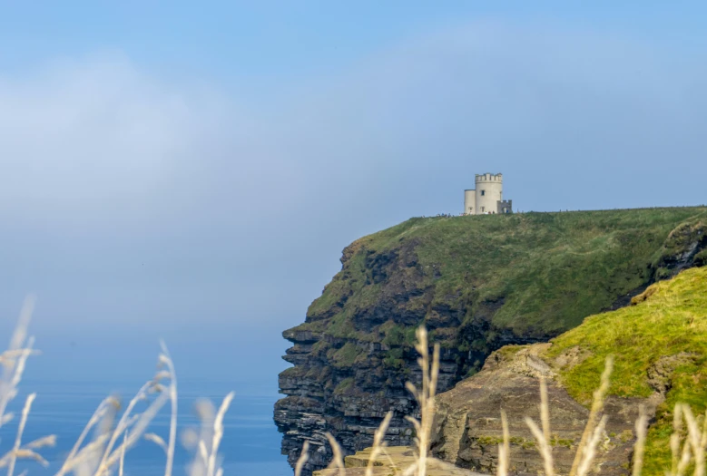 a grassy cliff with an unusual building sitting atop it