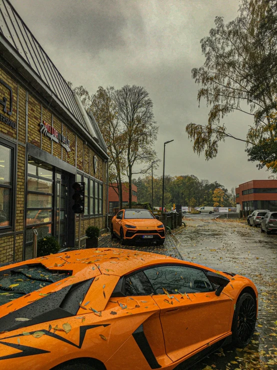 an orange car is parked on a rainy street