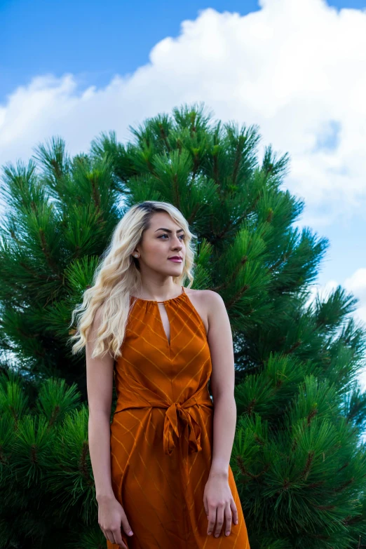 a blond woman wearing a orange dress posing for a picture