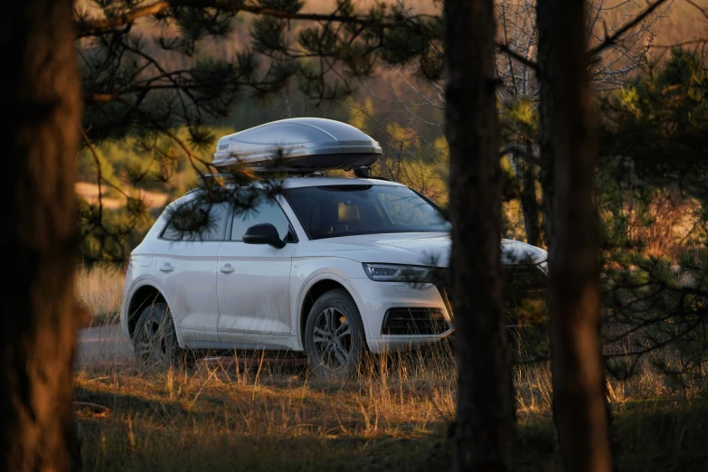 the large white car has a canoe strapped to it's roof