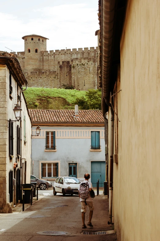 a man is walking down a street with an old castle in the background