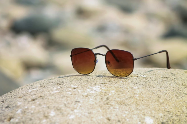 one pair of sunglasses that is laying down on top of a rock