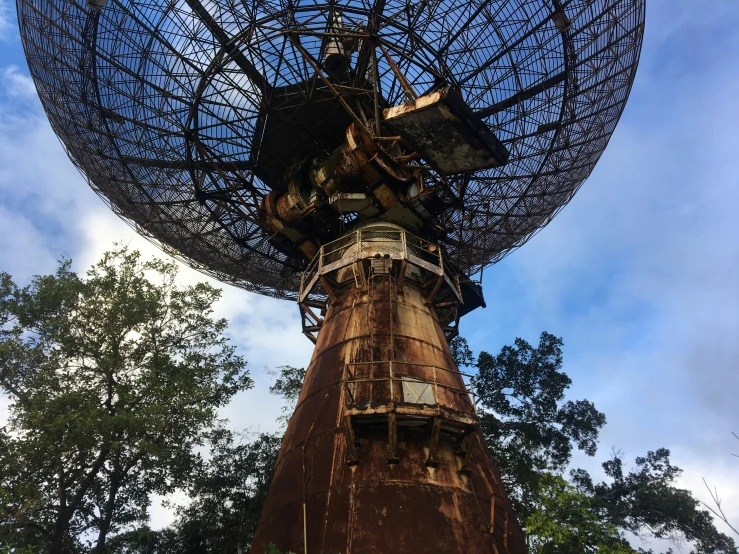 a large metal object with trees in the background