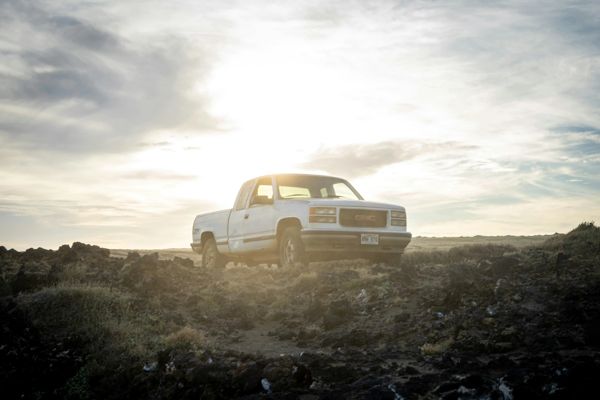 the truck is parked in the field next to the rock