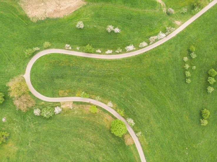 an aerial s of the winding road in a field