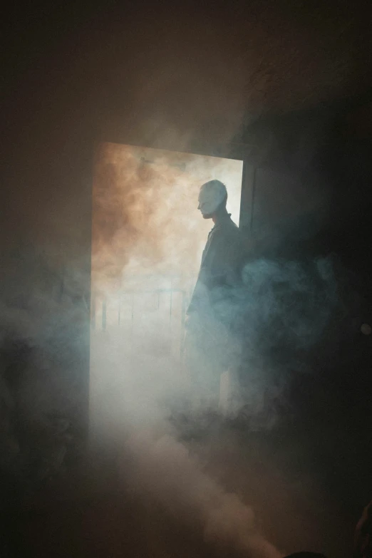 a man standing in a dark room with light on and fog coming out