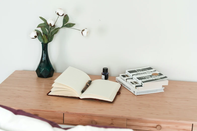 a desk topped with books and a vase filled with flowers