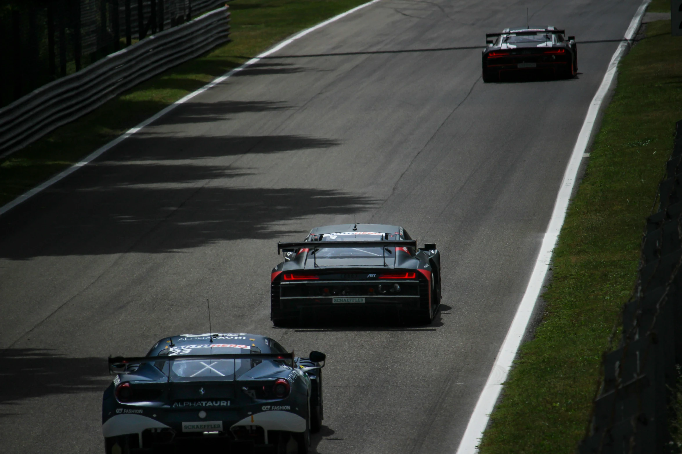 a couple of racing cars driving down a race track