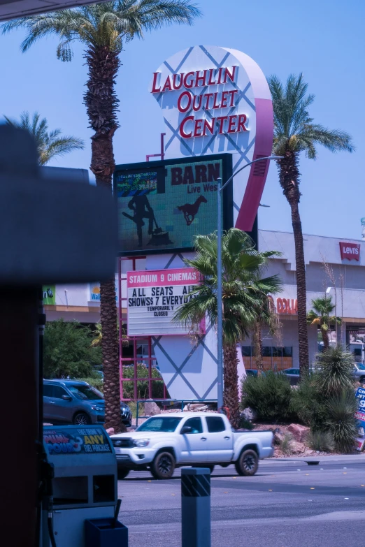 a sign in the center of an intersection near palm trees