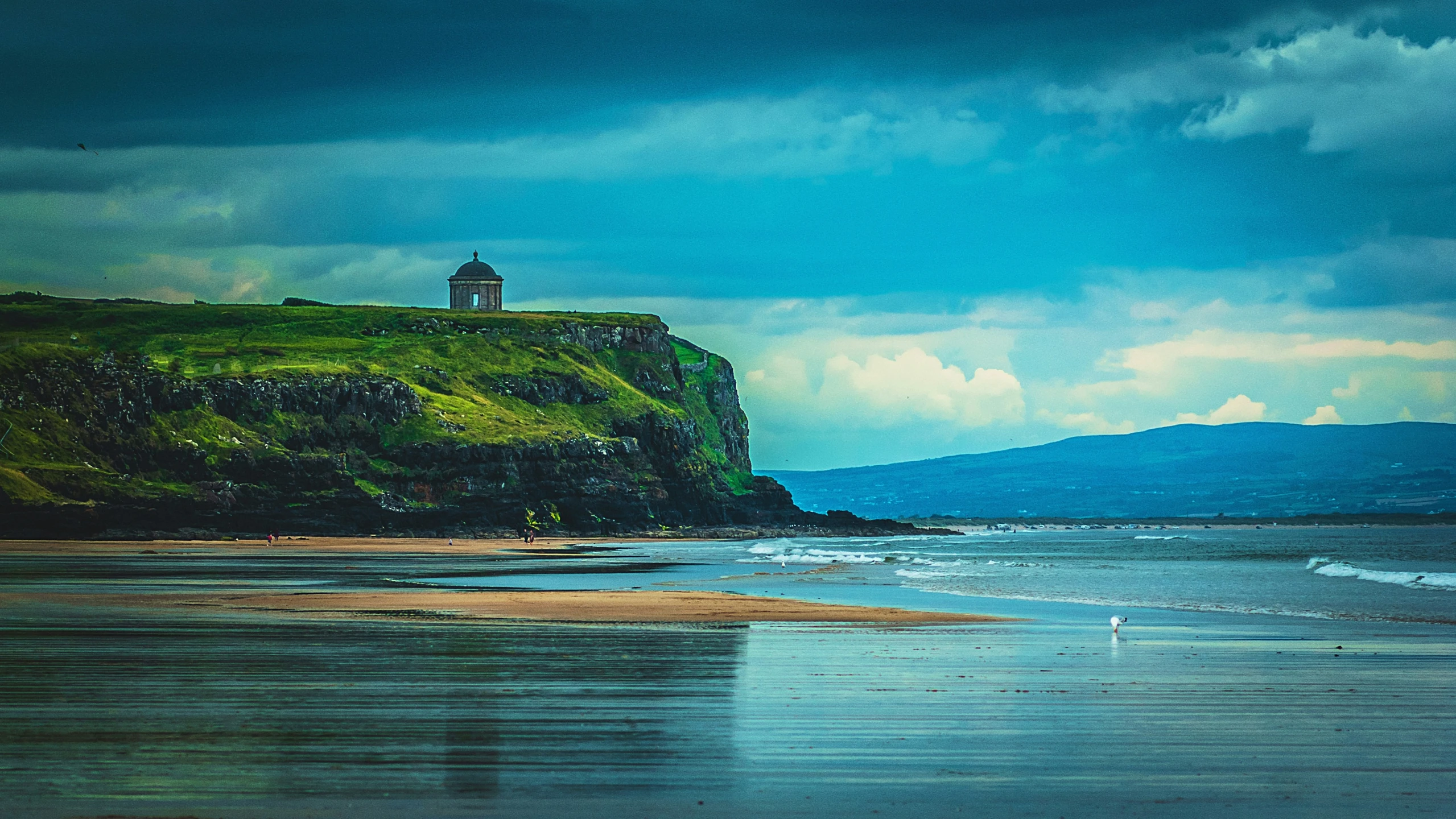 a lighthouse perched on top of a cliff near a beach