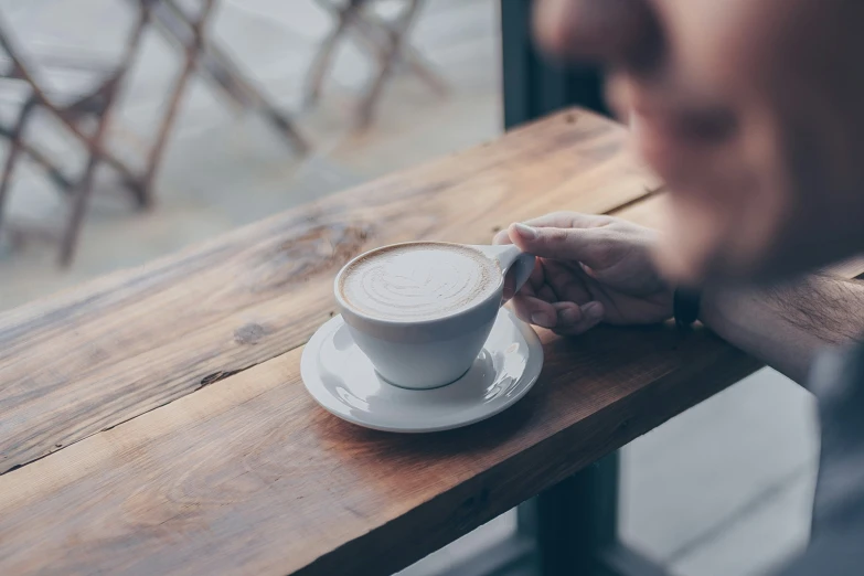 the man is sitting at the table holding his cup of coffee