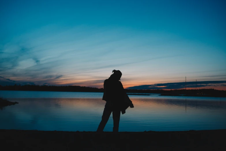 a person standing in front of water at sunset