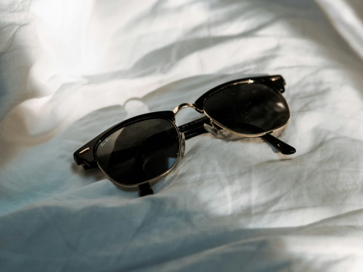 pair of black sunglasses lying on white sheets