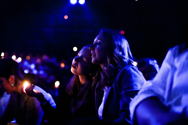 a group of women sitting next to each other holding cell phones