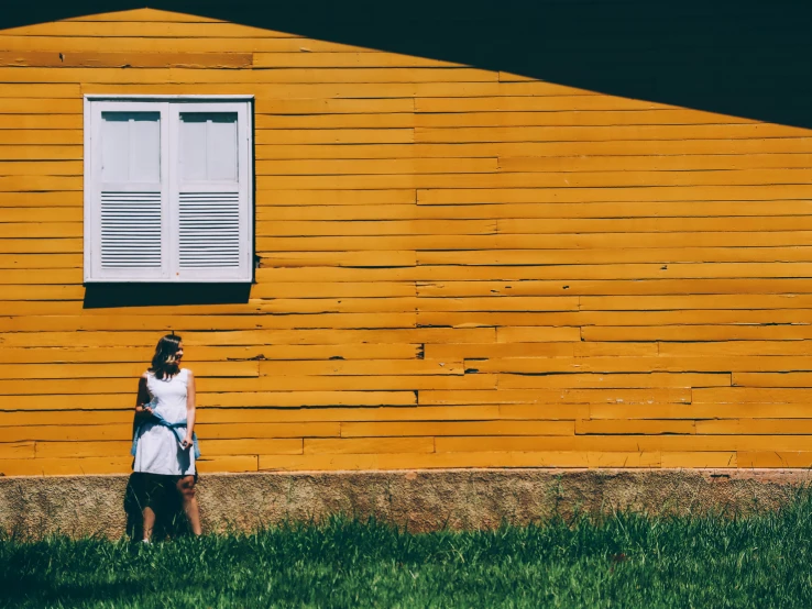 a person in white shirt standing by a wall with a window and a black and white cat