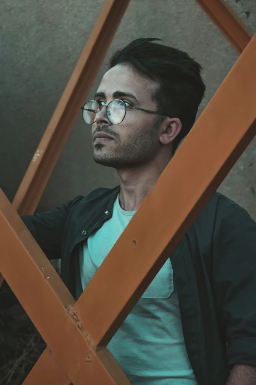 man in black jacket and glasses looking out through a wooden window