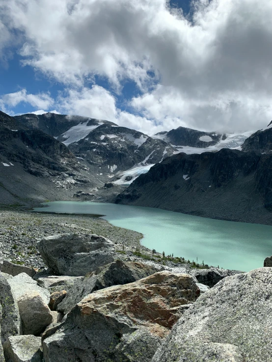 mountains with water under cloudy skies next to it