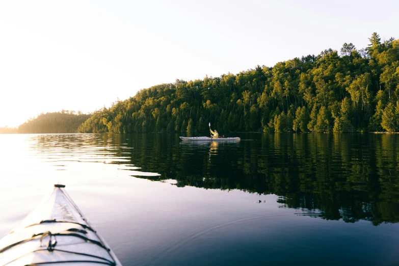 the person is paddling their canoe on the calm waters