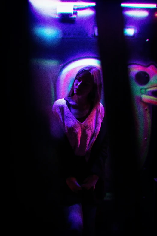 a girl standing in front of a row of brightly colored lights