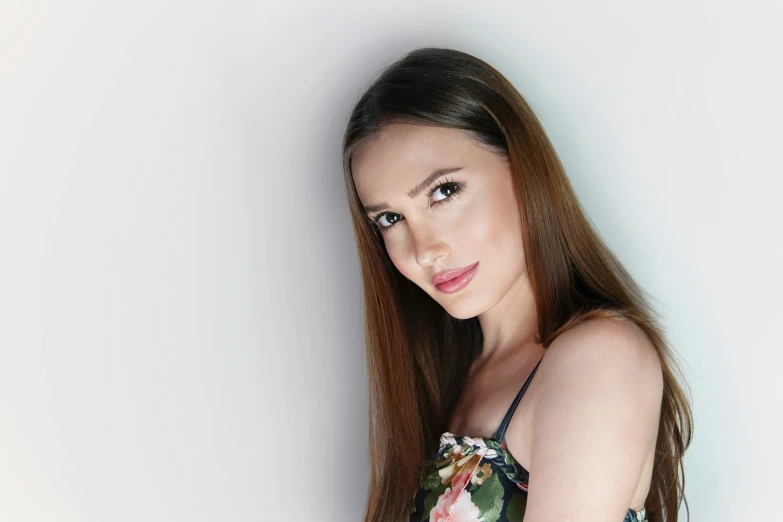 a woman is wearing a floral top in front of a white wall