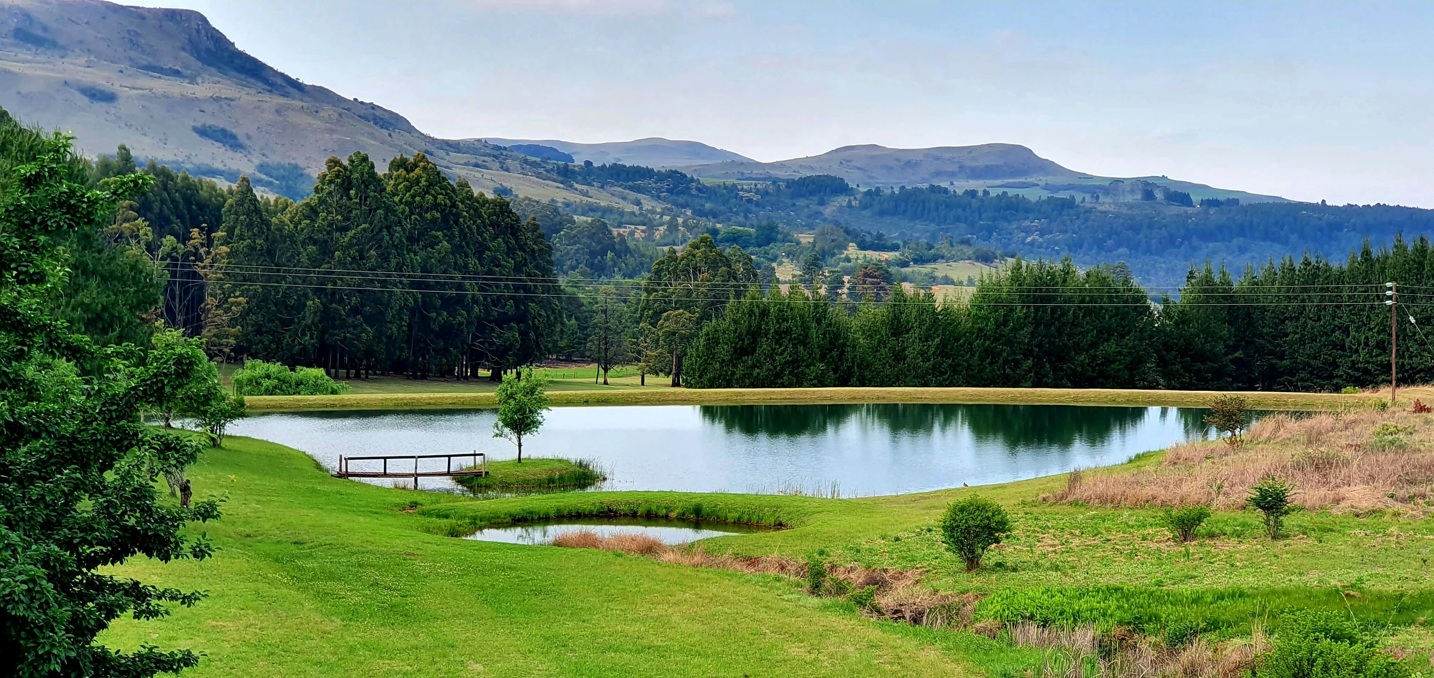 an empty park bench by the water and hills