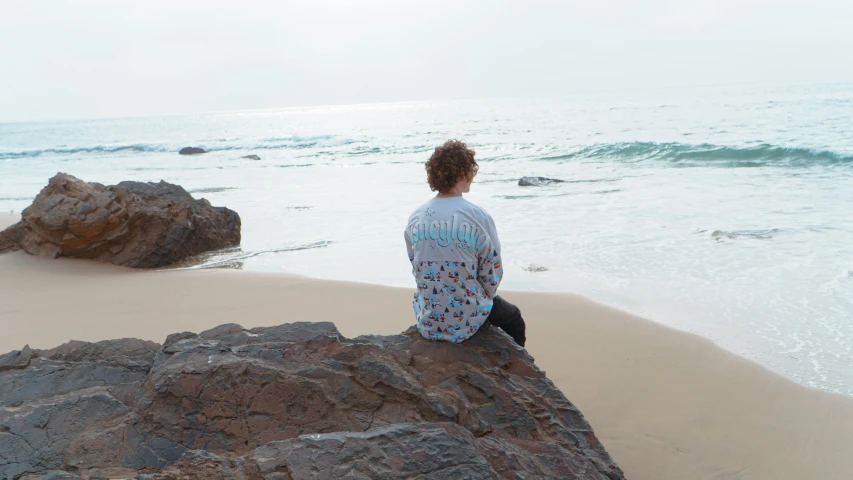 man sitting on rocks looking out over the ocean