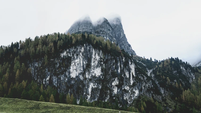 a group of mountains sitting behind a green field