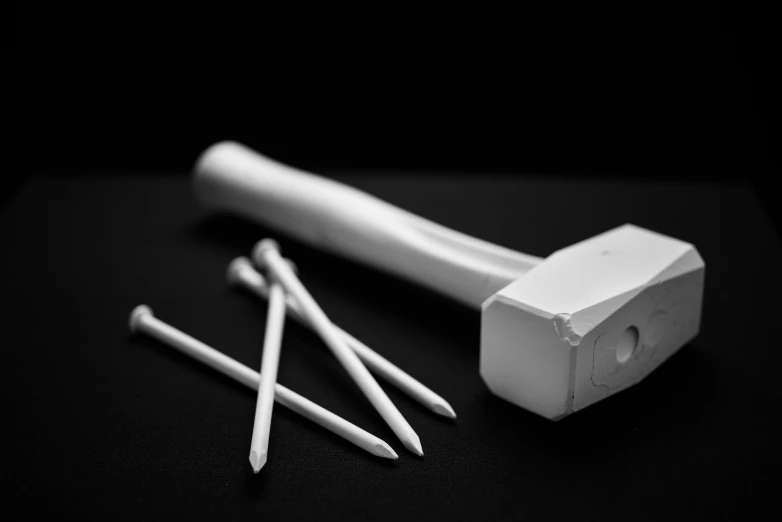 a hammer and some white long nails are laid out on the table