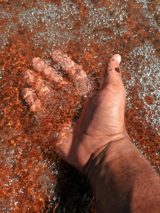person walking barefoot on wet beach with orange mud