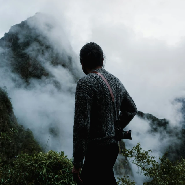 man stands in front of the mist covered mountain