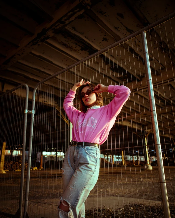 a girl leaning against a metal fence posing for the camera