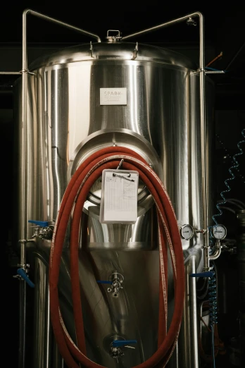 a stainless steel tank with a red hose on the side