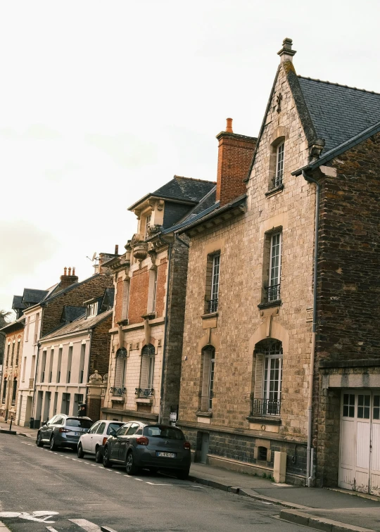 a row of old buildings line the street with cars parked in front