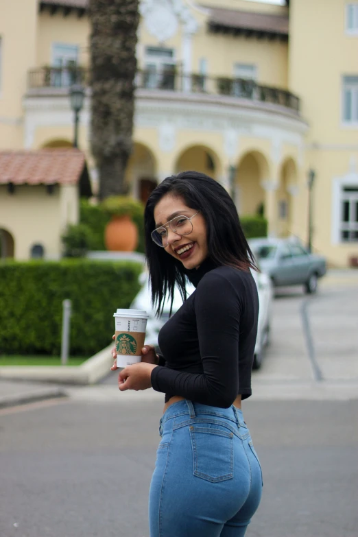 a woman holds her coffee cup and smiles