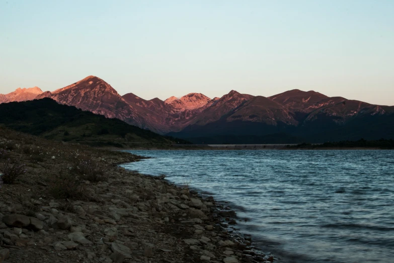 the mountains of a town are visible behind a body of water