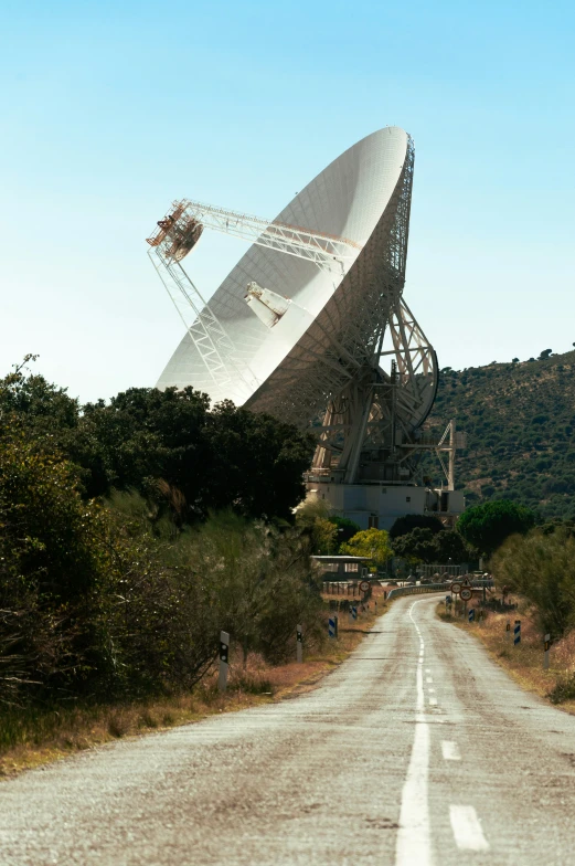 a large antenna dish in the middle of a rural road